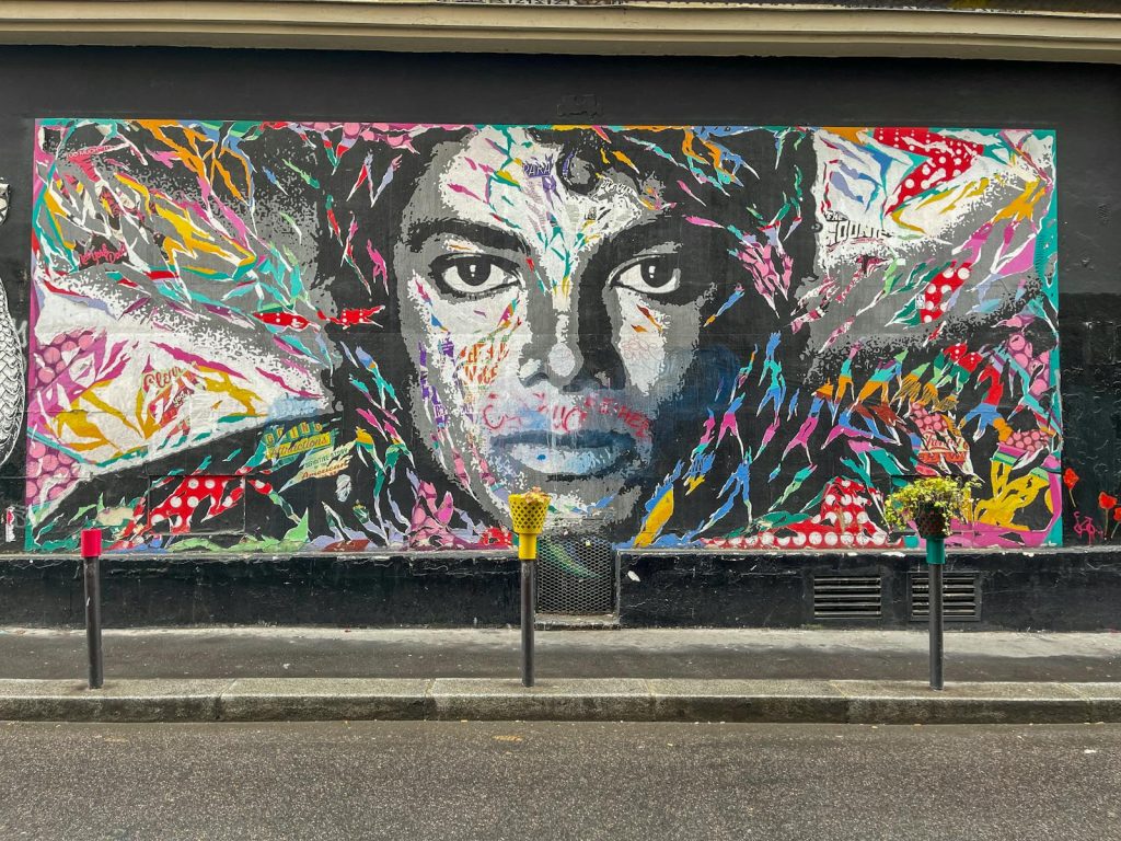 Vibrant mural of a face painted on a wall in Montmartre, Paris, showcasing dynamic street art style.